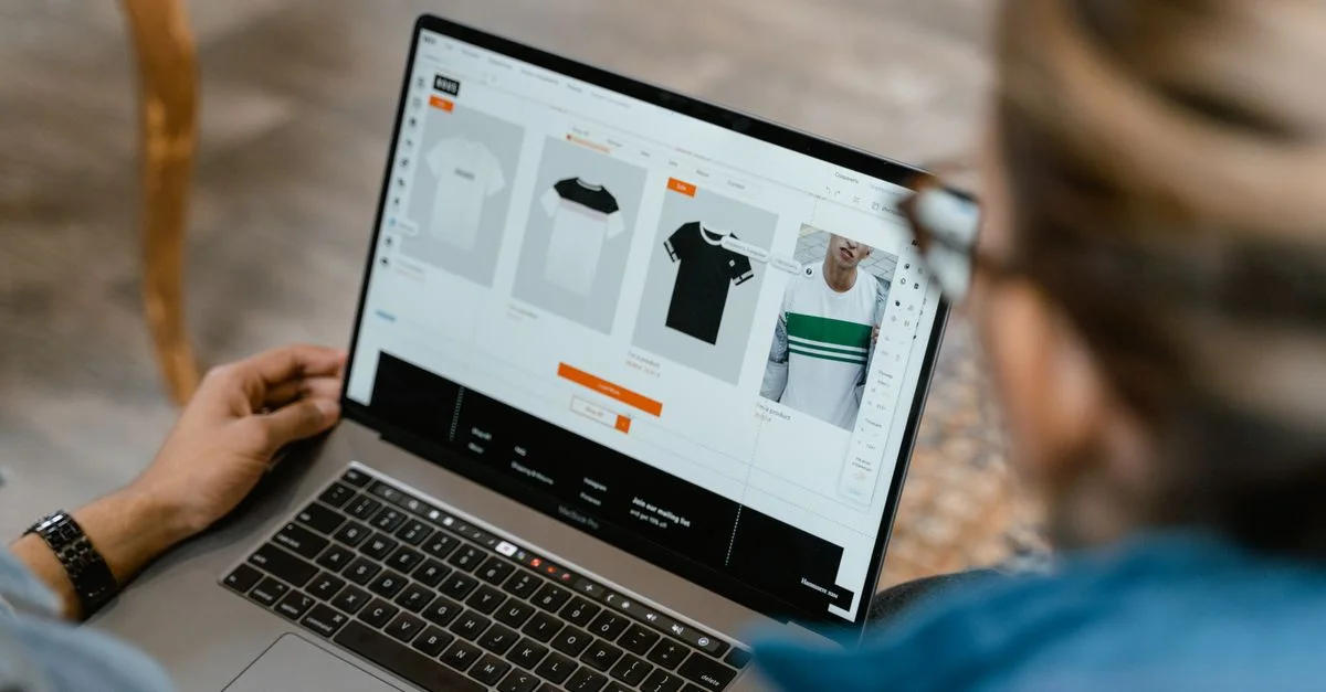 Deux personnes collaborant sur un ordinateur portable pour la création et la sélection de t-shirts.